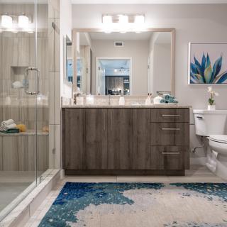 A modern bathroom with a large mirror, wooden vanity, and decorative elements.