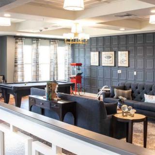 A stylish lounge area featuring modern furniture, a pool table, and a popcorn machine.