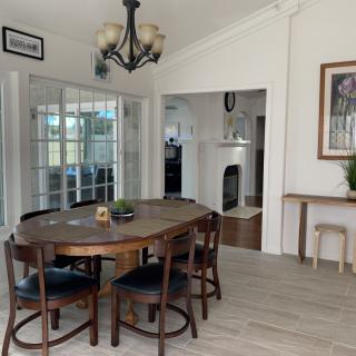 A cozy dining room with a wooden table and chairs, featuring a chandelier and glass doors leading to another room.