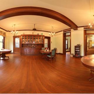 A vintage-style dining room featuring wooden floors, a bar area, and elegant chandeliers.