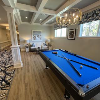 A stylish recreation room featuring a blue pool table and elegant chandelier.
