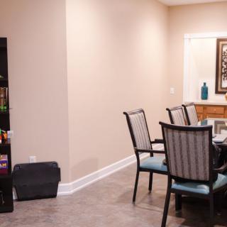 A cozy dining room with a set of chairs around a table and a bookshelf nearby.