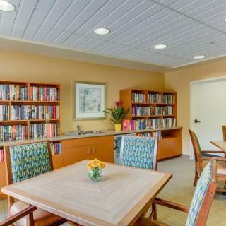 A cozy library with bookshelves, tables, and chairs for reading.