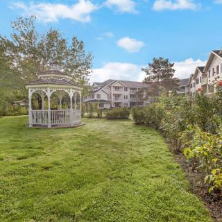 A scenic view of a garden with a gazebo and residential buildings in the background.