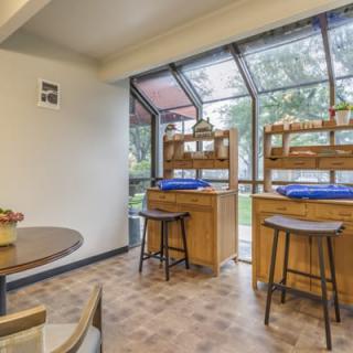 A cozy dining area with wooden furniture and large windows letting in natural light.