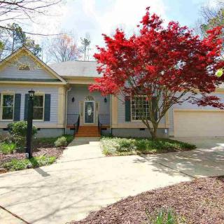 A charming suburban house with a well-maintained front yard and a tree with vibrant red leaves.