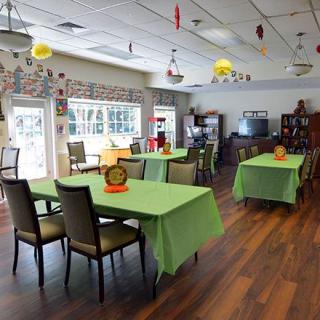 A brightly decorated dining area with green tablecloths and wooden flooring.