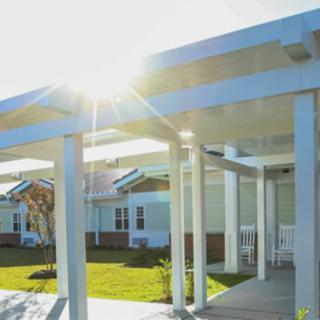 Sunlit view of modern housing with a pergola.