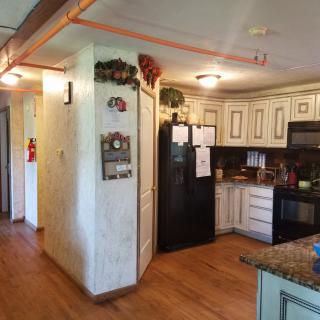 A cozy kitchen with wooden floors, white cabinets, and a black refrigerator.