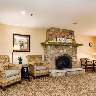 A cozy lobby area featuring a stone fireplace, comfortable chairs, and warm decor.