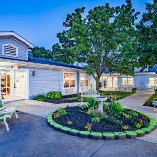A well-lit building with a beautifully landscaped garden in the evening.