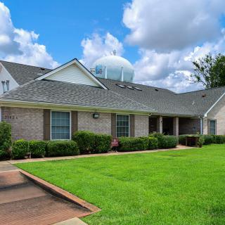 A suburban brick house with a well-maintained lawn and a clear blue sky.