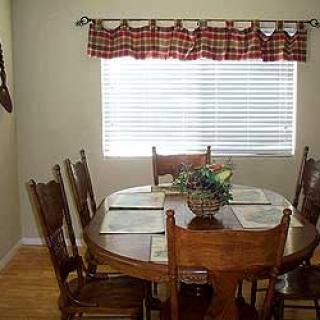 A cozy dining room with a wooden table and chairs near a window with plaid curtains.