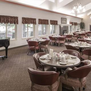 An elegant dining room with neatly arranged tables and a grand piano.