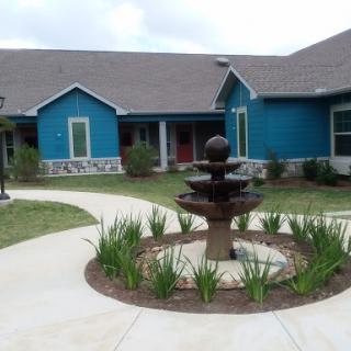 A beautiful residential building featuring a central fountain surrounded by landscaped greenery.