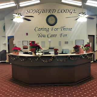 A decorated lounge reception area with a clock and text on the wall.