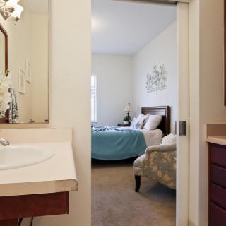 A view from the bathroom into a cozy bedroom with a neatly made bed.