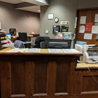 A reception area with wooden counter and computer stations in the background.