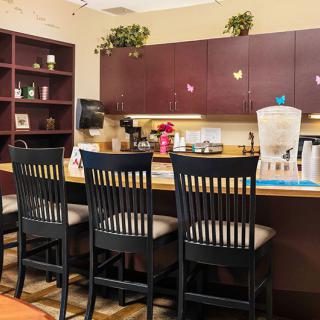 A cozy kitchen area with a counter and high chairs, featuring cabinets and a coffee maker.