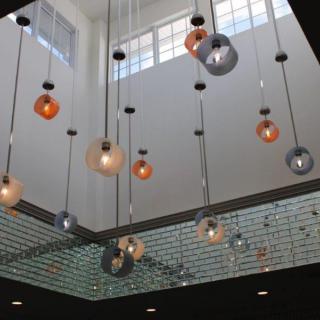 A modern ceiling featuring an array of pendant lights with various colors and sizes, enhancing the contemporary aesthetic of the room.