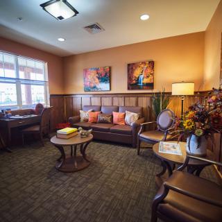 A cozy living room with warm lighting, featuring a comfortable sofa, decorative pillows, and artwork on the walls.
