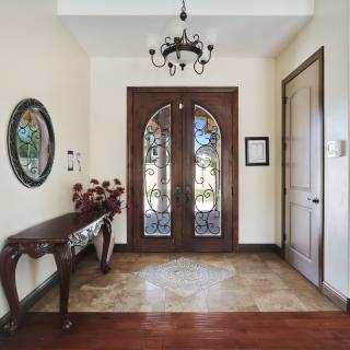 An elegant entryway with a chandelier, ornate double doors, and a decorative console table.