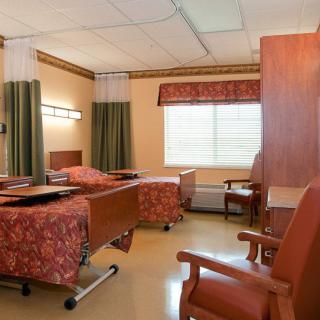 A hospital room with two beds, curtains, and chairs arranged neatly.