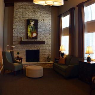 A cozy living room with a brick fireplace, armchairs, and warm lighting.
