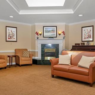 A cozy living room with a sofa, fireplace, and piano.