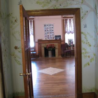 View through an open door into a room with wooden floors and a fireplace.