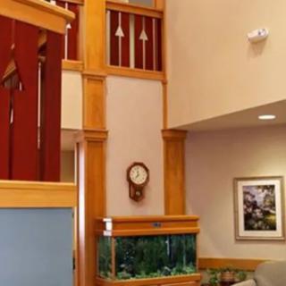 A cozy living room with wooden accents, featuring an aquarium and a wall clock.