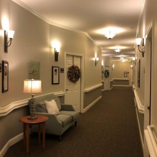 A warmly lit hallway with chairs, lamps, and decorative elements along the walls.