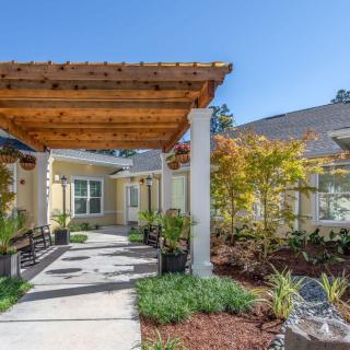 A residential building entrance with a wooden pergola and landscaped garden.