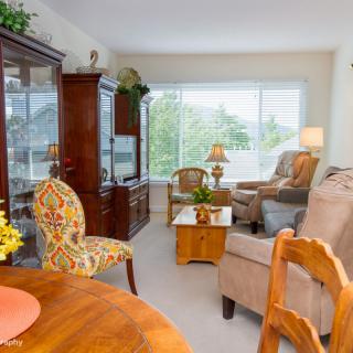 A bright and cozy living room with elegant wooden furniture and large windows offering a scenic view.