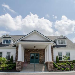 A residential building with a triangular roof and stone accents under a partly cloudy sky.