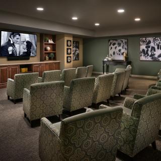 A cozy home theater room with patterned chairs and a large screen for watching movies.