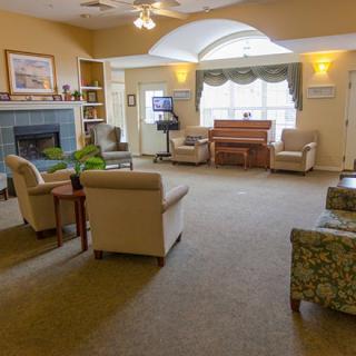 A cozy living room with comfortable seating and a piano near the window.