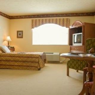 A cozy hotel room with a bed, television, and seating area.
