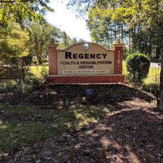 Entrance sign for Regency Health and Rehabilitation Center, surrounded by trees and greenery.