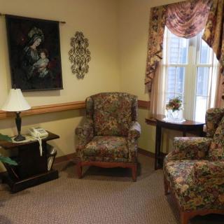A cozy, traditionally decorated living room with patterned chairs, a small table, and wall art.