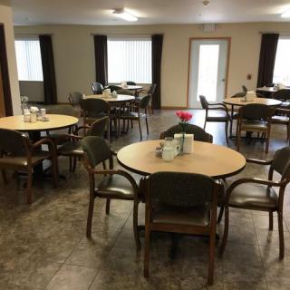 A spacious dining area with several round tables and chairs, suitable for communal gatherings.