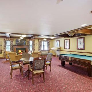 A cozy recreation room with a pool table, seating area, and fireplace.
