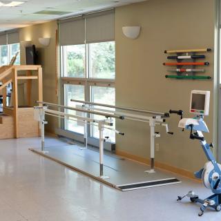 A rehabilitation center featuring parallel bars and exercise equipment for physical therapy.