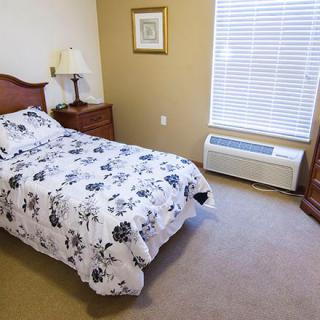A cozy bedroom with a single bed, nightstand, and window.