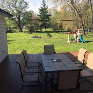 A sunny backyard with a patio set and children's playground.