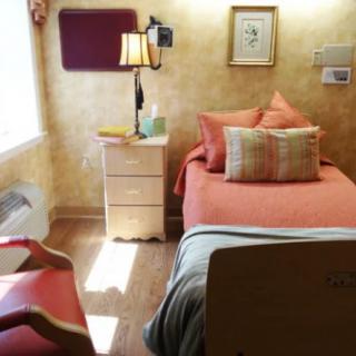 A cozy bedroom with a single bed, nightstand, and warm lighting.