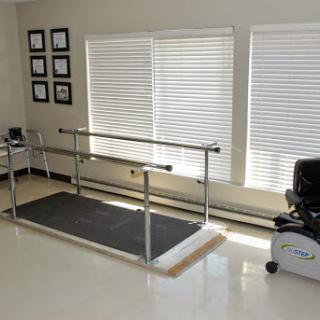 A rehabilitation therapy room equipped with a walking barre and exercise bike.