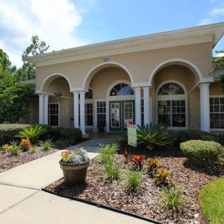 A beautiful entrance to a well-designed building, surrounded by lush landscaping and vibrant plants.
