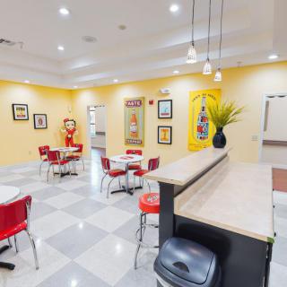 A retro-themed diner interior with red and white seating, vibrant yellow walls, and classic decor.
