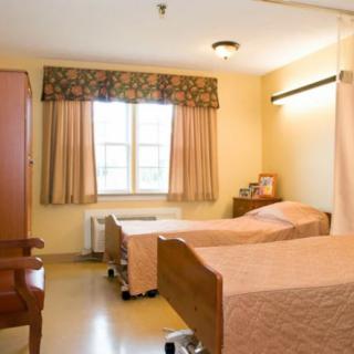 A hospital room with two beds and a window with curtains.